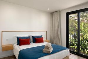 a bedroom with a large bed with blue and red pillows at Marco 4 Seasons- Summer in Arco da Calheta +15 photos
