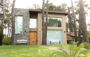 ein kleines Haus mit einer Bank im Gras in der Unterkunft Los Patitos in Mar de las Pampas