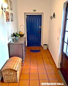 a hallway with a blue door and a bench at Prédio do Castelo in Caloura