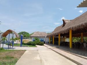a restaurant with a thatched roof and tables and chairs at Dulce Barú in Ararca