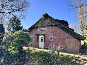 a small red brick house with a thatched roof at Ferienwohnung im Reetdachhaus, Burhave in Burhave