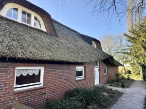 an old brick house with a thatched roof at Ferienwohnung im Reetdachhaus, Burhave in Burhave