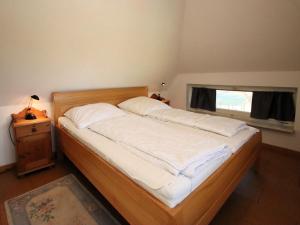 a bedroom with a bed with white sheets and a window at Ferienwohnung im Reetdachhaus, Burhave in Burhave