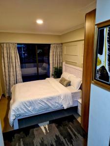 Un dormitorio con una cama blanca con una ventana. en Homely Spot Nairobi West, en Nairobi 10 fotos más