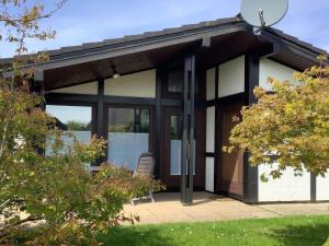 a house with glass doors and a chair in a yard at Freistehender Ferienbungalow im Fachwerkstil in Burhave