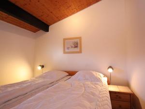 a bed in a bedroom with two lights on at Freistehender Ferienbungalow im Fachwerkstil in Burhave