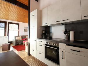 a kitchen with white cabinets and a living room at Freistehender Ferienbungalow im Fachwerkstil in Burhave