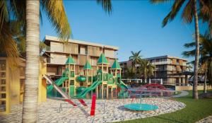 einen Spielplatz vor einem Gebäude mit Palmen in der Unterkunft Resort Gav Muro Alto - PE in Ipojuca