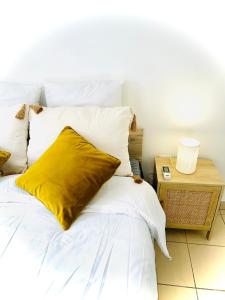 a white bed with a yellow pillow on it at T2 ILONA - neuf, 8min airport in Saint-Denis