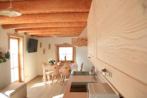 a kitchen and dining room with wooden ceilings at Baita il nido dell'aquila in Fierozzo