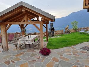 a wooden gazebo with a table and a bench at Baita il nido dell'aquila in Fierozzo