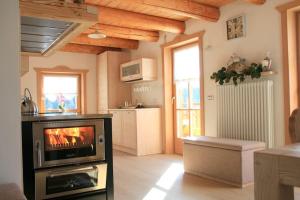 a living room with a television and a kitchen at Baita il nido dell'aquila in Fierozzo