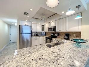 クリアウォーター・ビーチにあるOceanfront Condo Sleeps 6 Walk To Beach Poolのキッチン(白いキャビネット、花崗岩のカウンタートップ付)