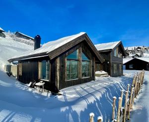 a log cabin with snow on the ground at Modern cabin at Høgevarde panoramic view, fireplace and EV station in Granheim