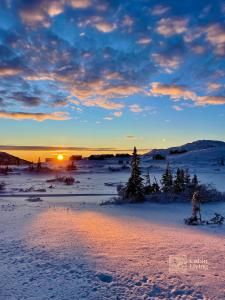 a person on skis in the snow at sunset at Modern cabin at Høgevarde panoramic view, fireplace and EV station in Granheim