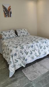 a bed with a blue and white blanket and pillows at Chalés Boca Da Mata in Piatã