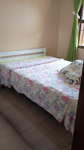 a bed with a floral bedspread on it in a room at Casa albatroz Imbé in Imbé