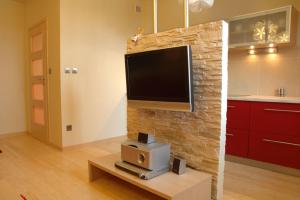 a living room with a tv on a brick wall at Apartment 28 Rubinowy Pod Aniołem in Kazimierz Dolny