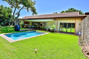 a house with a swimming pool in a yard at CasaDulce Zimbali- Exquisite 4 bedroom home with expansive yard and pool in Ballito