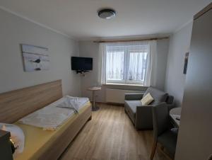 a bedroom with a bed and a chair and a television at Pension & Restaurant Haus Hiddensee in Kloster