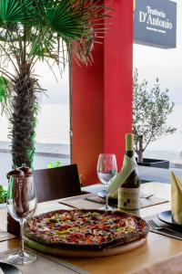 a pizza sitting on a table with a bottle of wine at Hotel Kokkino Nero in Kókkinon Nerón