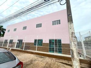 a pink building with a fence in front of it at Quarto em frente aeroporto Efatá Shalom in Campo Grande