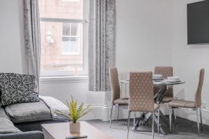 a living room with a couch and a table with chairs at Peterhead Pad - SJA Stays - Modern 2 Bed Apartment in Peterhead