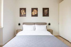 a bedroom with a white bed with four pictures on the wall at Appartamento Louis in Verona