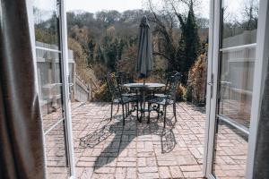 a patio with a table and an umbrella at Riverbank Cottage in Ironbridge