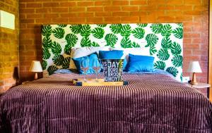 a bedroom with a bed with blue pillows at Chalé Jequitiba, hidro, lareira, natureza, Sul de Minas, Café da manhã in Sapucaí-Mirim