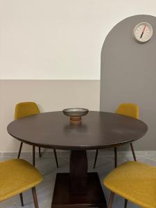 a table with yellow chairs and a clock on the wall at SnappyB Living Spaces in Alexandroupoli