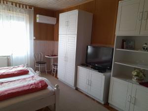 a bedroom with a bed and a tv and white cabinets at Anatan Apartmanok Harkány in Harkány