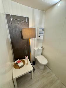 a bathroom with a toilet and a table with a lamp at Un repos au cœur du Périgord vert in Varaignes +3 photos