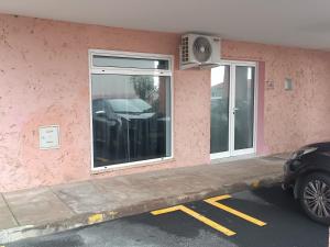 a car parked in front of a pink building at Kings B&B Eiras in Caniço
