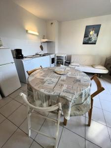 una cucina con tavolo e sedie e una cucina con frigorifero di Résidence Les Vagues - 059 - Appartement idéalement situé à 50 m des plages Soulacaises MAE-4371 a Soulac-sur-Mer