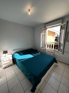 una camera da letto con un letto blu e una finestra di Résidence Les Vagues - 059 - Appartement idéalement situé à 50 m des plages Soulacaises MAE-4371 a Soulac-sur-Mer