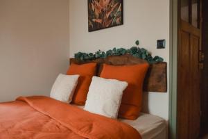 a bedroom with a bed with orange pillows at Le Charme - Petite Maison in La Ferté-Bernard