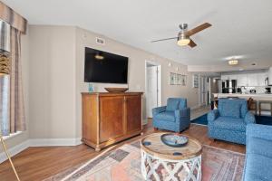 a living room with a flat screen tv and blue chairs at Bahama Sands 1204 in Myrtle Beach