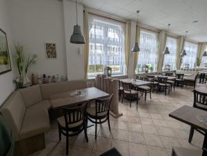 a restaurant with tables and chairs and windows at Pension & Restaurant Haus Hiddensee in Kloster