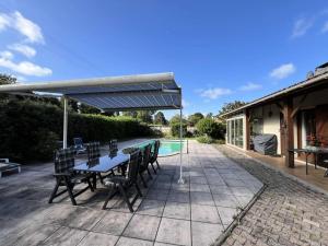 eine Terrasse mit Tisch und Stühlen und einem Pool in der Unterkunft Résidence 104-grayan Et L Hopital - 104 - Agréable villa avec piscine dans un quartier calme MAE-6111 in Grayan-et-lʼHôpital