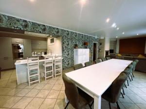 a kitchen and dining room with a white table and chairs at Villa 114 with heated pool in Ploegsteert
