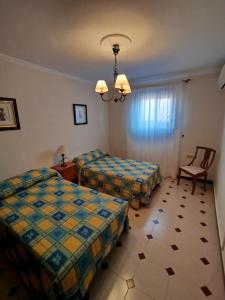 a hotel room with two beds and a chair at Merino Casa Rural in Yunquera