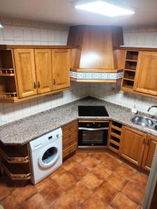 a kitchen with wooden cabinets and a washer and dryer at Merino Casa Rural in Yunquera +8 photos