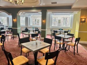 a restaurant with tables and chairs and windows at Carlisle Station Hotel, Sure Hotel Collection by BW in Carlisle