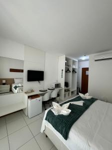 a bedroom with a bed and a desk and a television at Studio Iloa Vista Piscina 015v in Barra de São Miguel +46 photos