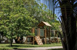 a wooden playground in a park with a tree at Studio Iloa Vista Piscina 015v in Barra de São Miguel