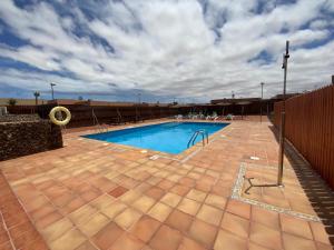 a swimming pool on a patio with a cloudy sky at Villa Bejeque & Barbecue in La Oliva