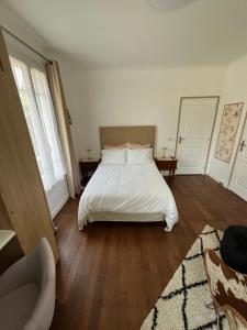 a bedroom with a bed with white sheets and wooden floors at Chambre villa du sentier in Pomponne