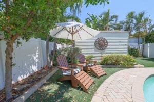 two chairs and an umbrella next to a pool at Heated Pool Villa-Walk to Beach-Tiki Bar-Sleeps 8 in Pompano Beach