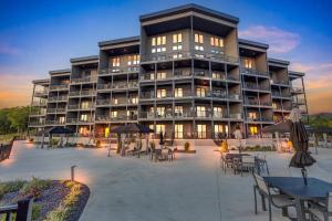 a large apartment building with tables and umbrellas at Whispering Waters Condo in Lake Ozark